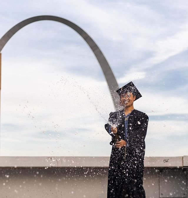 Anh Nguyen célèbre son diplôme universitaire avec l'emblématique Gateway Arch de Saint-Louis en arrière-plan.