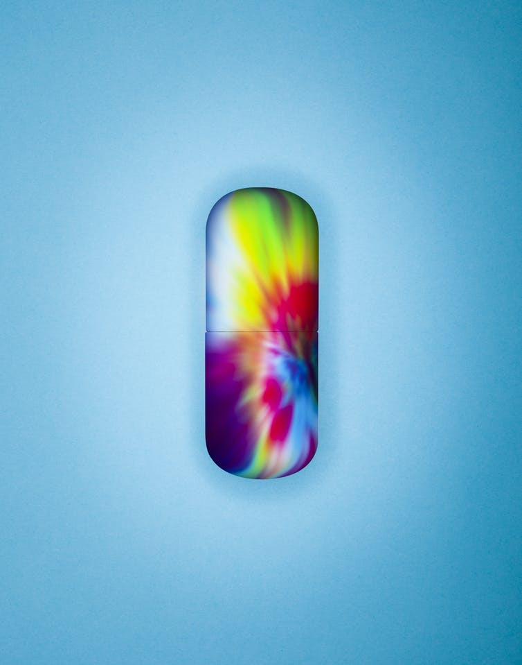 Capsule de pilule arc-en-ciel sur fond bleu.