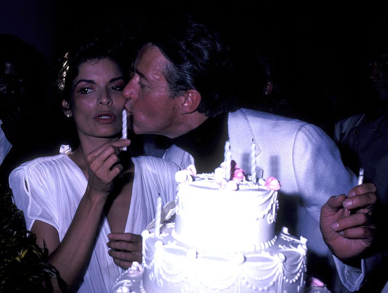 Halston embrasse Bianca Jagger sur la joue derrière son gâteau d'anniversaire.