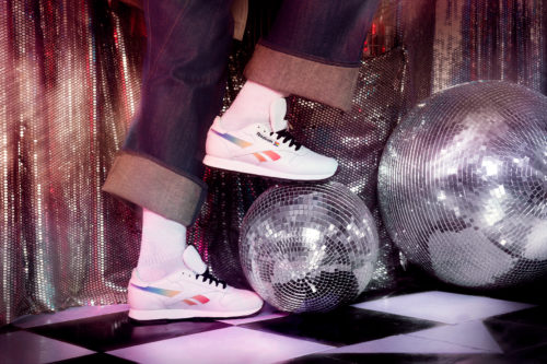 Modèle portant des baskets Reebok Pride Club C tout en marchant sur une boule disco