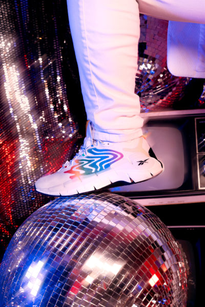 Modèle portant des baskets Reebok Zig Kinetica II tout en marchant sur une boule disco