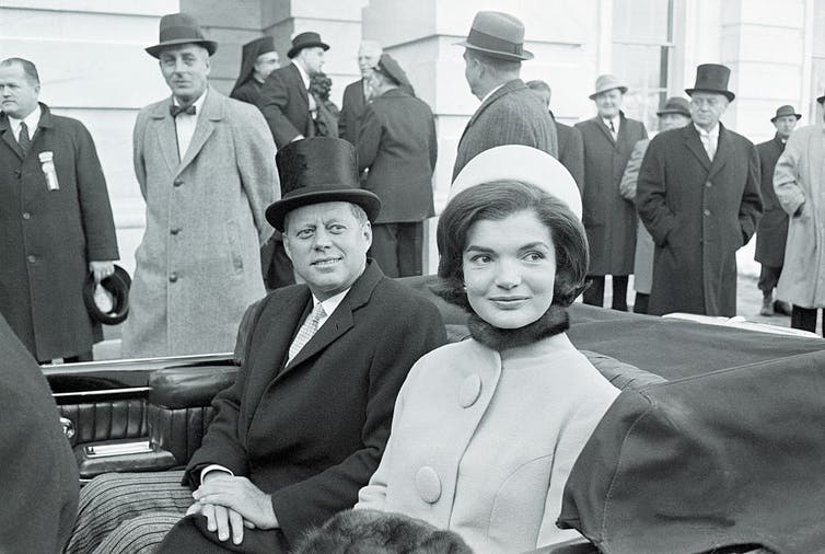 Jackie Kennedy monte dans une voiture aux côtés de John F. Kennedy.