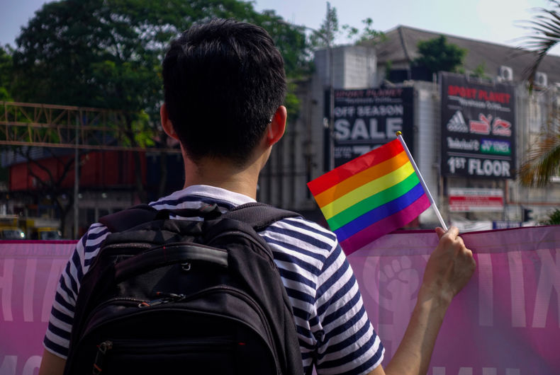 Un jeune homme agite tranquillement un petit drapeau arc-en-ciel à #WomensMarchMY à l'occasion de la Journée internationale de la femme 2019