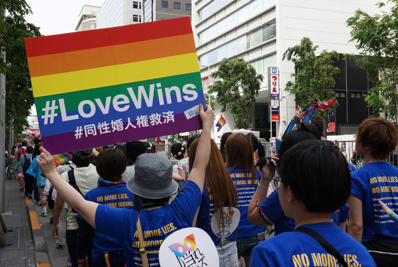 Personne tenant l'affiche arc-en-ciel Love Wins pour les droits du mariage homosexuel chez les personnes marchant dans le Tokyo Rainbow Pride (TRP) Parade 2016 à Shibuya, Tokyo, Japon.
