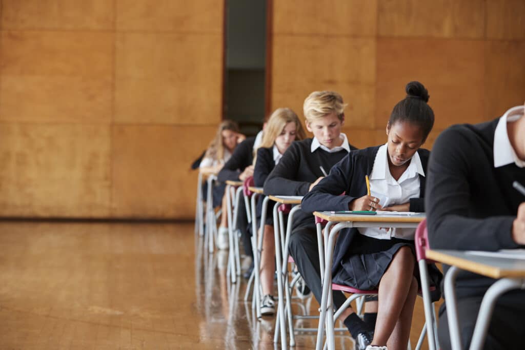 Les étudiants adolescents en uniforme d'examen assis dans la salle de l'école