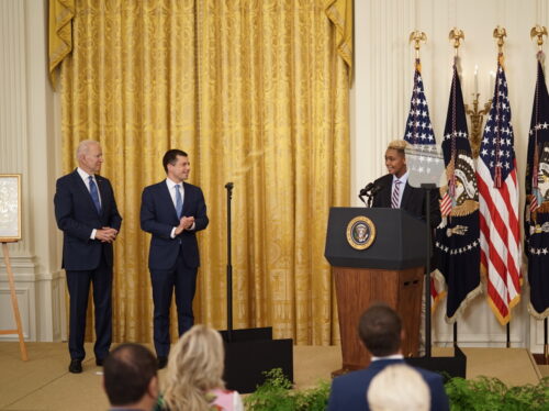 Le président Joe Biden (à gauche) et le secrétaire aux Transports Pete Buttigieg applaudissent Ashton Mota, 16 ans, alors que Mota s'adresse à la foule rassemblée dans la salle Est de la Maison Blanche