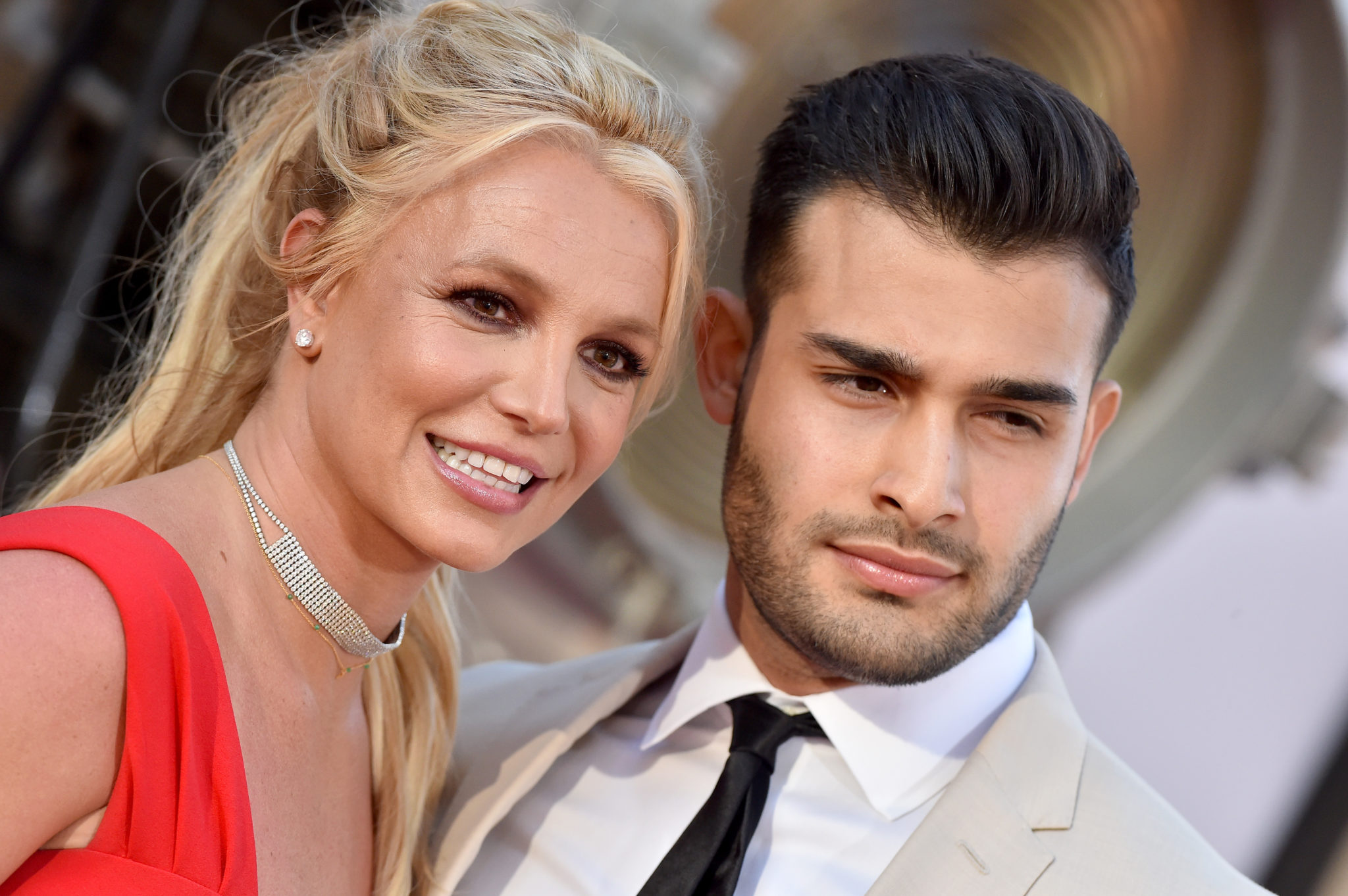 Gros plan de Britney Spears et de son petit ami Sam Asghari souriant sur le tapis rouge