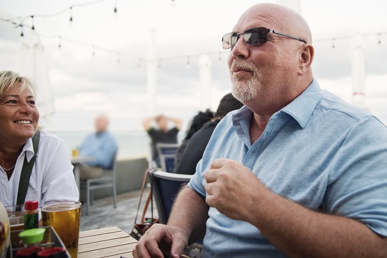 Homme et amis savourant un repas ensemble sur une terrasse de restaurant.