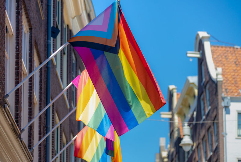 Drapeau de la fierté du progrès (nouveau design du drapeau arc-en-ciel) ondulant dans les airs avec un ciel bleu, communauté LGBTQ aux Pays-Bas