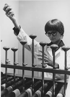Photo en noir et blanc d'une femme utilisant une grande pipette pour mesurer un liquide chimique.