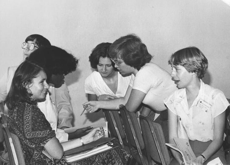 Photo en noir et blanc de six jeunes femmes discutant de manière informelle tout en assistant à une conférence.