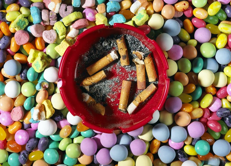 Cigarettes dans un cendrier au sommet de bonbons