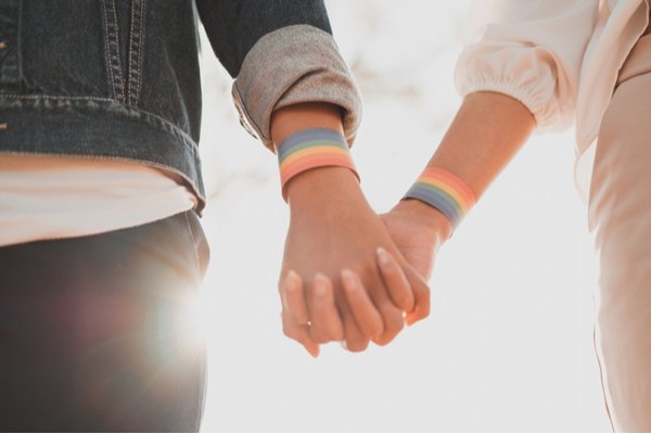 couple main dans la main avec des bracelets arc-en-ciel