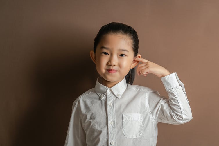 petite fille mettant son doigt dans son oreille
