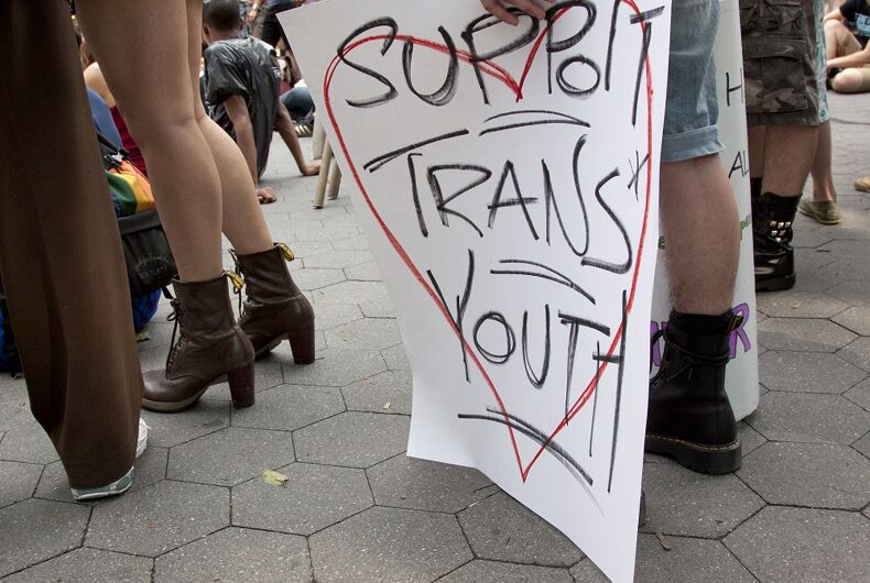 : Un supporter tient une pancarte indiquant "Soutenir les jeunes trans"