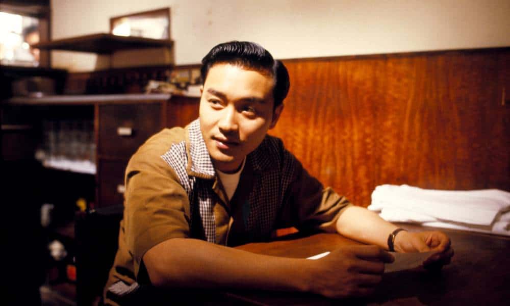 Leslie Cheung, un homme asiatique, est assis à un bureau pendant le tournage d'un film