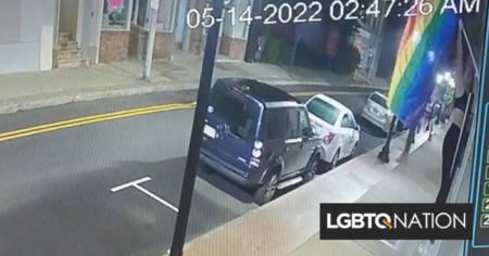 Une femme grimpe sur le rebord de la fenêtre pour voler le drapeau arc-en-ciel des maris homosexuels