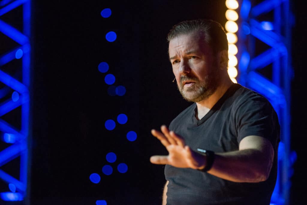 Ricky Gervais fait des gestes en se produisant sur scène