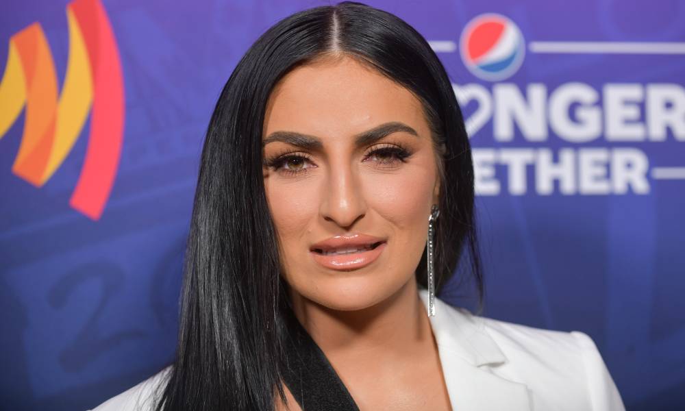 La superstar de la WWE Sonya Deville regarde la caméra tout en portant une veste blanche