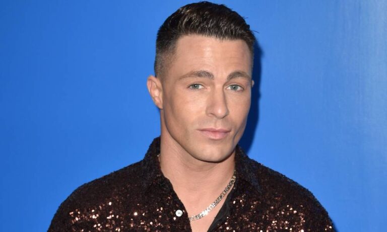Colton Haynes wears a brown sequinned shirt as he stands in front of a blue background