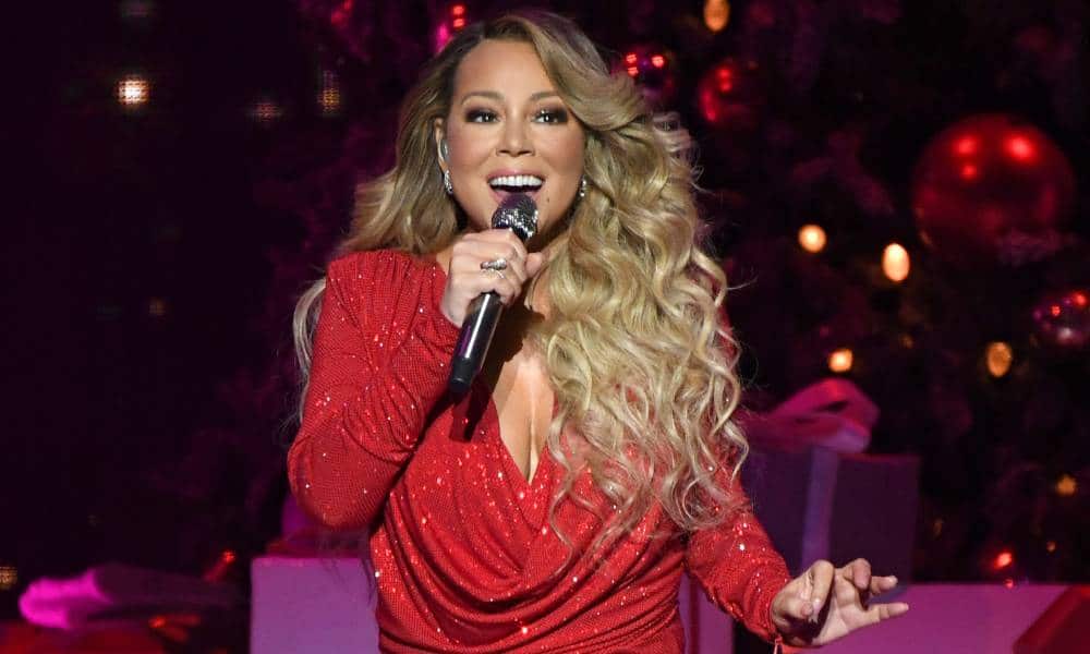 Mariah Carey poursuivie en justice pour 16 millions de livres sterling pour avoir volé All I Want For Christmas Is You Mariah Carey sings into a microphone that she holds in one hand while wearing a red sparkly dress amid a festive Christmas set on tour