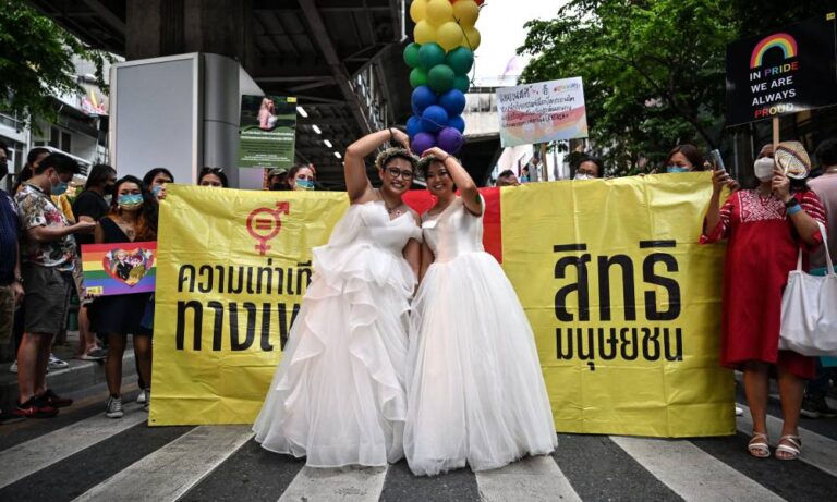 A same-sex couple poses in wedding dresses as members of the LGBTQIA+ community take part in the Pride March in Bangkok, Thailand