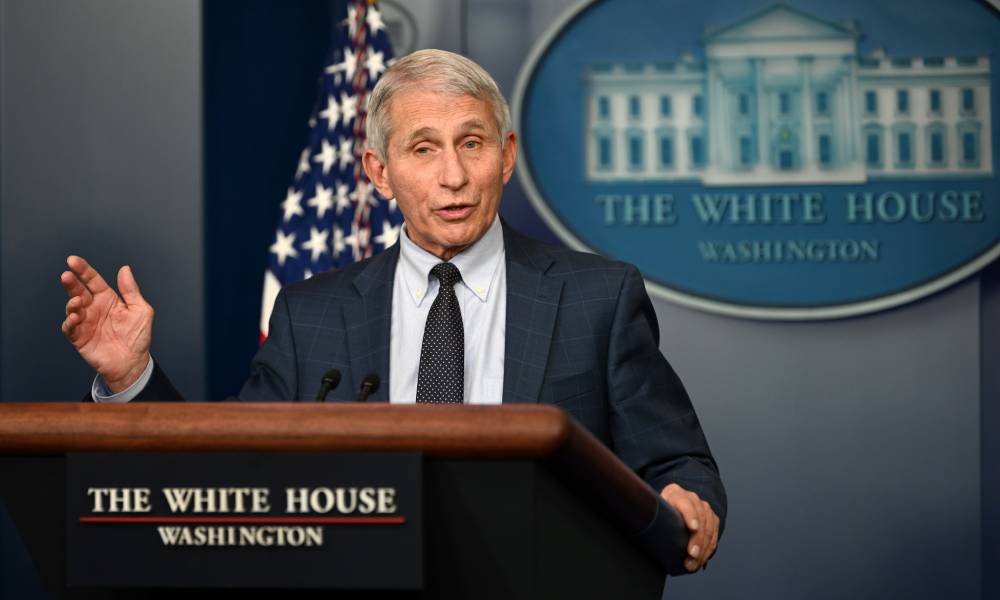Monkeypox: Anthony Fauci dit que les personnes LGBTQ + doivent être écoutées dans la lutte contre l’épidémie Anthony Fauci stands at a podium in the White House with the White House logo and an American flag in the background. Fauci is wearing a white shirt, dark tie and dark suit jacket as he talks to people off camera