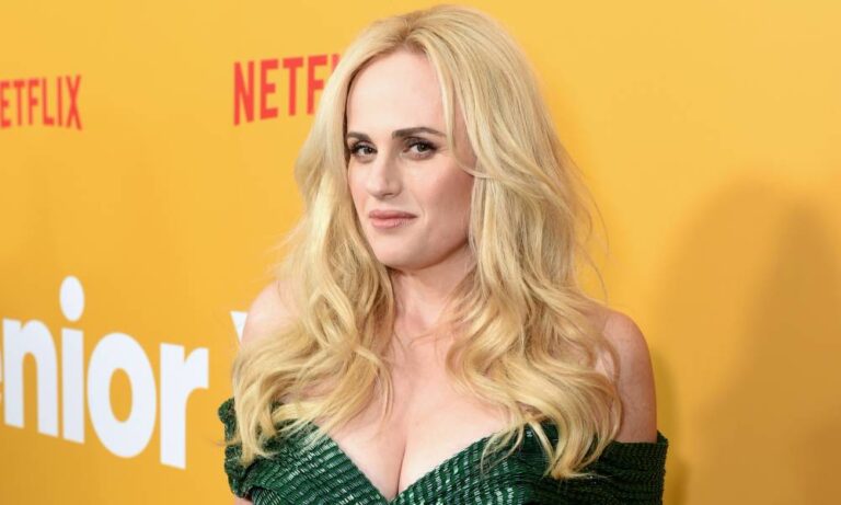 Rebel Wilson rompt le silence sur la « situation difficile » alors que le journal nie l’avoir « sortie » Rebel Wilson wears a green dress with her blonde hair down as she stands in front of a yellow background with the red Netflix logo in the background