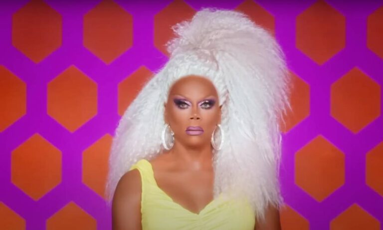 RuPaul dénonce les tentatives des républicains d’interdire aux enfants les spectacles de dragsters : « C’est une tactique de diversion » RuPaul wears a white blonde wig and yellow dress as the drag queen sits in front of a pink and orange patterned background