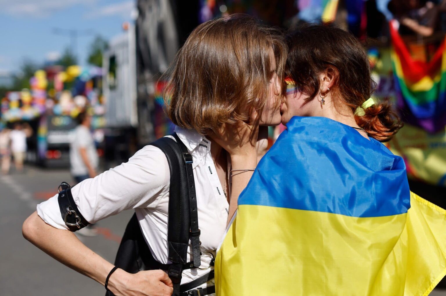 Des milliers de personnes s’unissent pour le défilé conjoint de la fierté LGBTQ+ polonaise et ukrainienne à Varsovie Two women, one of them wrapped into a Ukrainian flag, kis