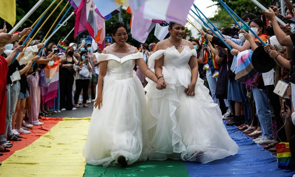 Les membres de la communauté LGBTQ + sont vêtus de robes de mariée alors qu'ils marchent sur une passerelle arc-en-ciel pendant qu'ils participent au défilé pour marquer le jour de la fierté 2022 à Bangkok, en Thaïlande