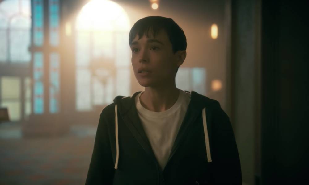 Elliot Page apparaît comme son personnage de l'émission Netflix The Umbrella Academy.  Le personnage, Viktor, porte un t-shirt blanc et un sweat à capuche bleu alors qu'il se tient à l'intérieur et parle à quelqu'un hors écran