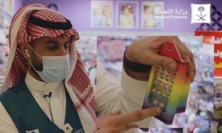 A Saudi Arabian official gestures towards a rainbow toy