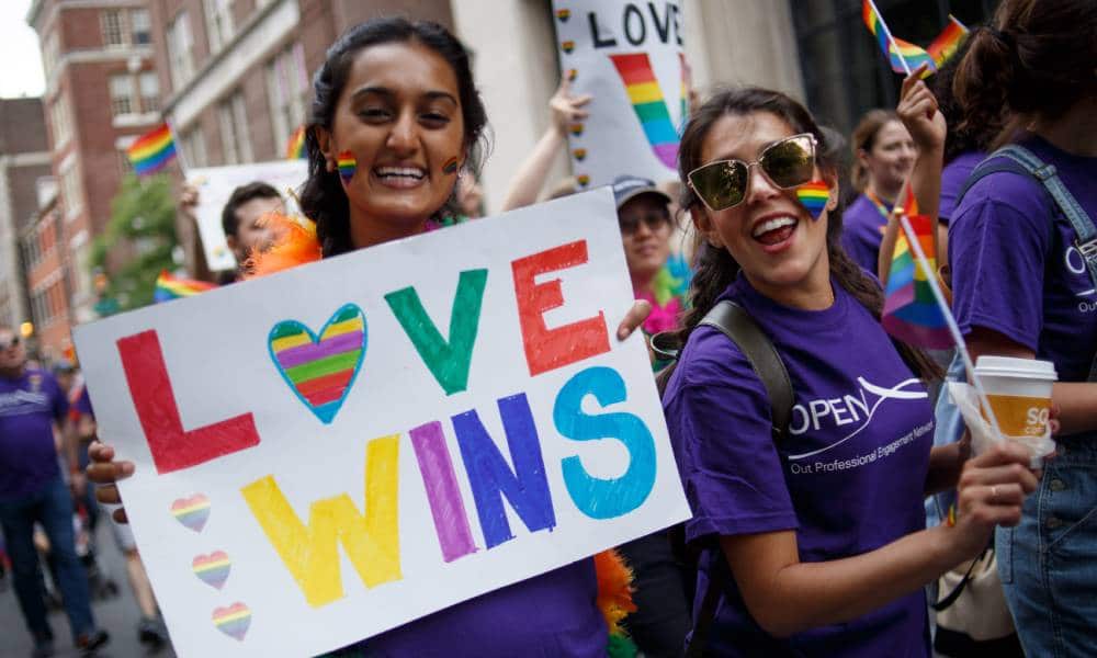 Les fêtards brandissent une pancarte indiquant "L'amour gagne" en lettres de couleur arc-en-ciel alors qu'ils participent au défilé de la fierté LGBT de Philadelphie à travers la ville "Quartier gay" et le quartier historique du centre-ville de Pennsylvanie