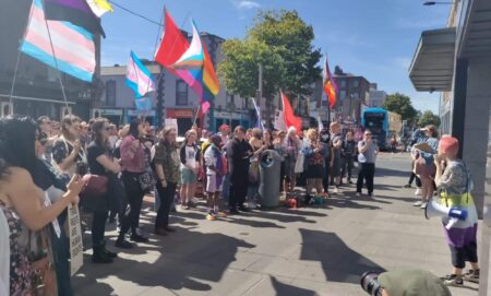 A crowd of LGBTQ+ activists and allies gather outside the Independent House
