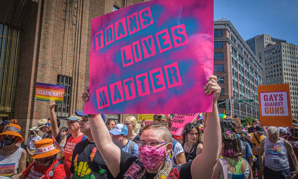 Les personnes trans reçoivent des kits d’autodéfense alors que l’épidémie de violence ne montre aucun signe de ralentissement Participant seen holding a pink coloured sign with blue lettering that reads "trans lives matter" at a protest