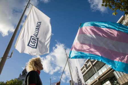 An activist holds a transgender pride flag at a protest by Transgender Action Block and supporters outside the first annual conference of the LGB Alliance