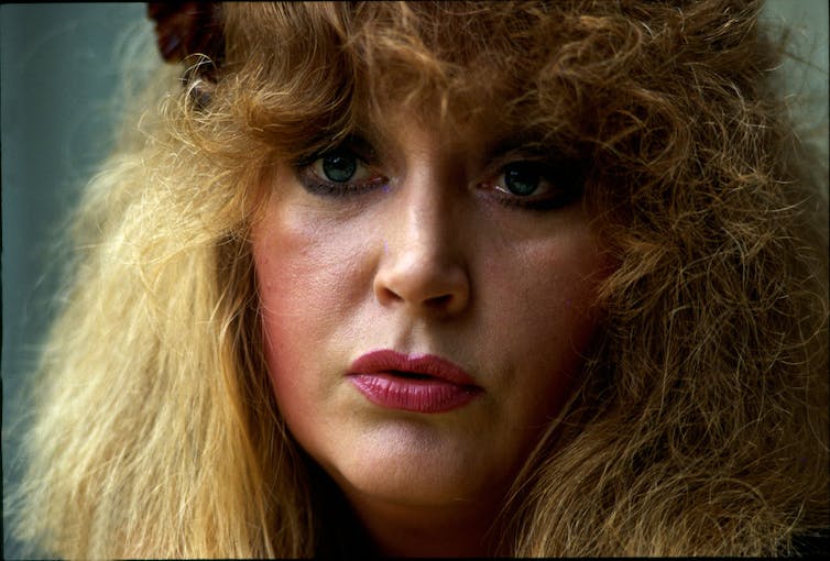 Portrait de femme aux cheveux blonds bouclés et aux larmes aux yeux.