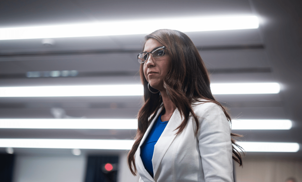 La représentante du Colorado, Lauren Boebert, porte une veste blanche et une tenue bleue alors qu'elle se tient dans une pièce