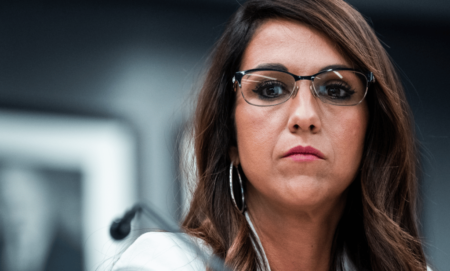 Colorado representative Lauren Boebert wears a white outfit as she stares somewhere off camera