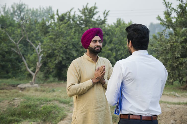 Un homme sikh se pliant les mains dans un namaste devant un autre homme.