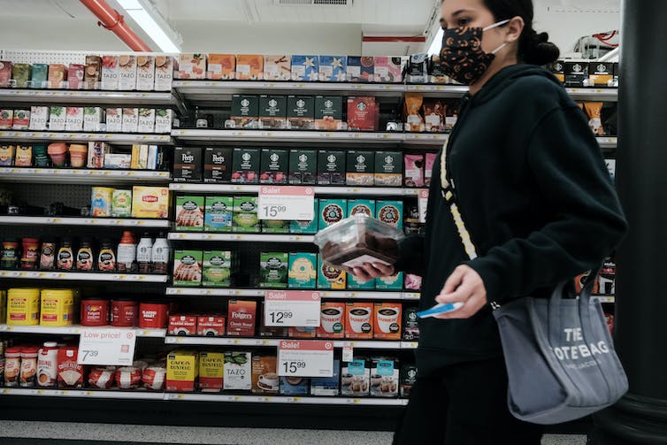 Une femme fait ses courses dans une épicerie en période d'inflation et de prix élevés de l'essence et de la nourriture.