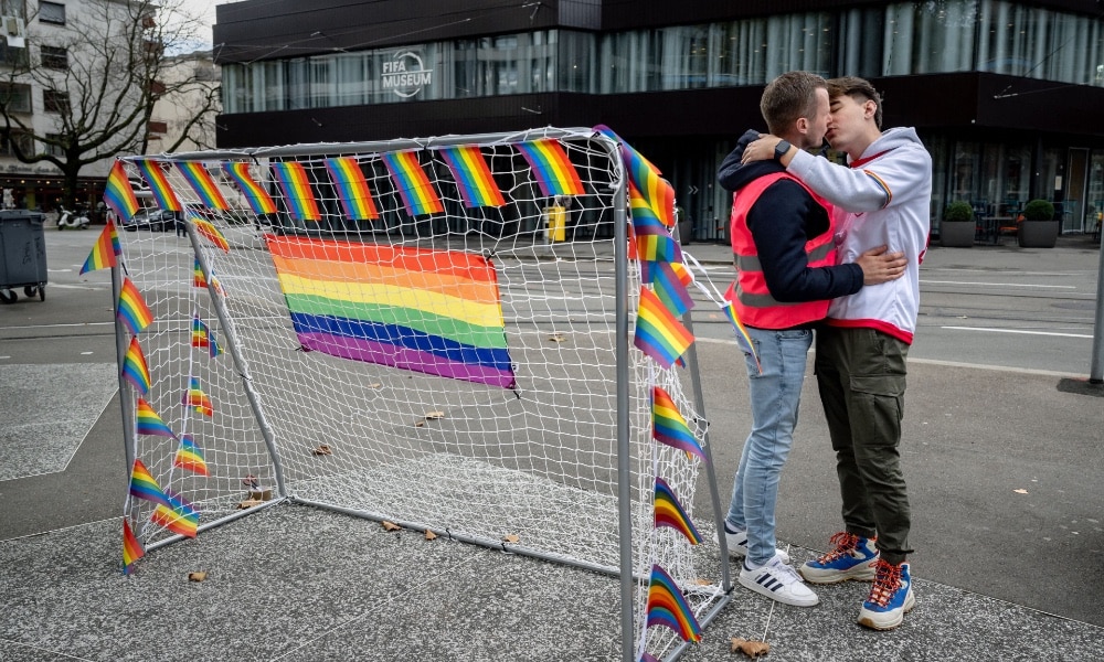 Deux hommes s'embrassent à Zurich devant un poteau de but et des drapeaux arc-en-ciel