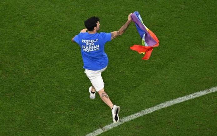 Un manifestant de la Coupe du monde du Qatar court sur le terrain en agitant un drapeau arc-en-ciel