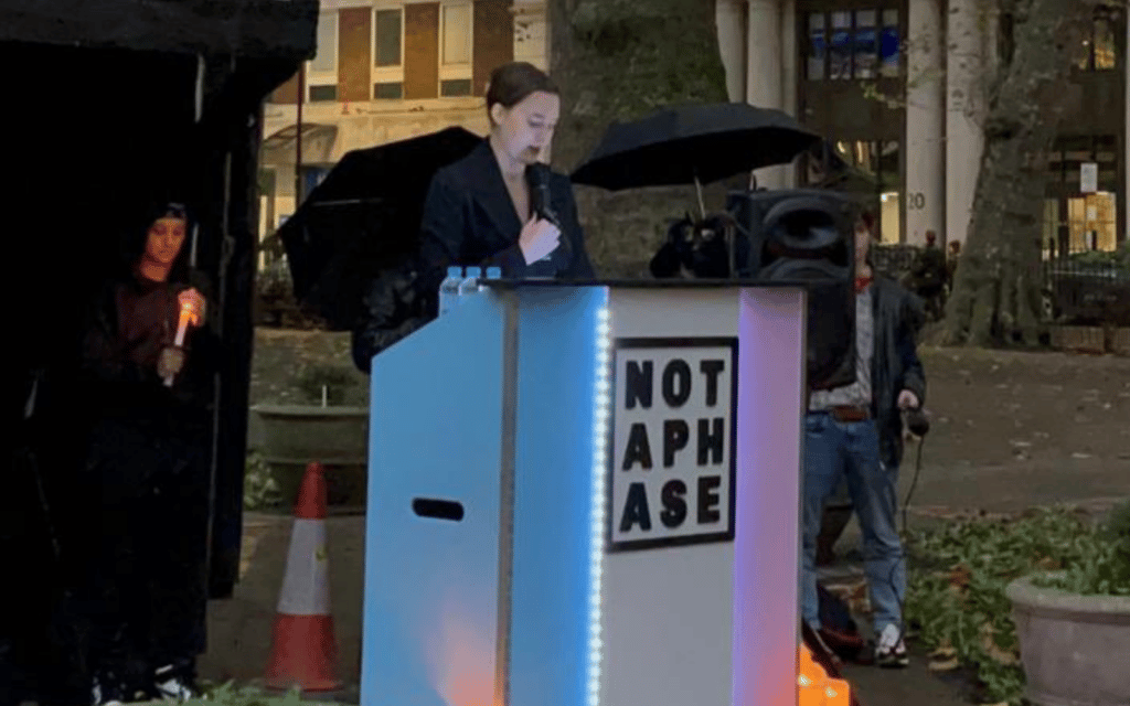 Une capture d'écran de Twitter montre Kate Litman s'exprimant sur un podium lors du Soho Trans Day of Remembrance.