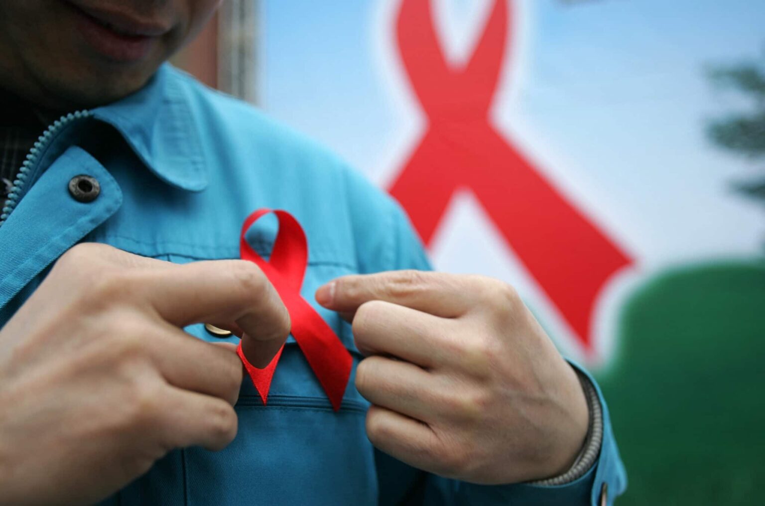 Journée mondiale de lutte contre le sida : le Parti travailliste annonce qu’il annulera la loi archaïque sur la fertilité pour les personnes vivant avec le VIH A photo of a person putting on a red ribbon for HIV AIDS awareness on World AIDS Day