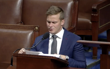 Dressed in a navy blue suit, white shirt and grey tie Madison Cawthorn gives his final address at the House of Representatives, sat a podium and talking into a microphone