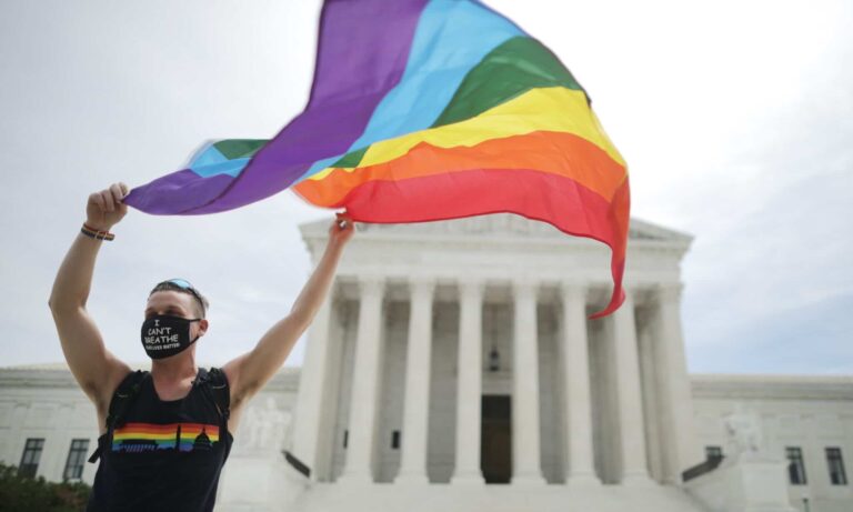 A person holds an LGBTQ+ Pride flag outside the US Supreme Court