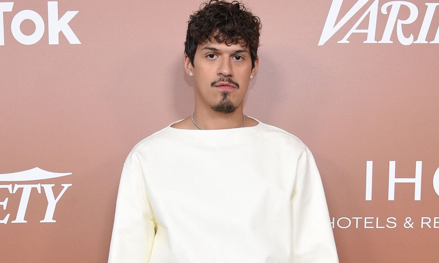 Omar Apollo admet qu’il avait le béguin pour l’acteur des Wizards of Waverly Place, David Henrie Omar Apollo wears a white top as he stares at the camera while standing in front of a rose pink background