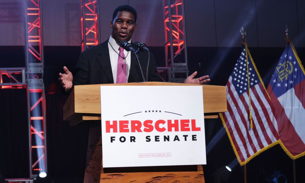 Herschel Walker se tient sur un podium avec une pancarte portant son nom après avoir perdu le second tour des élections au Sénat de Géorgie